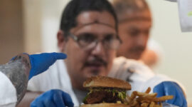 Narapidana Aaron Arroyo menyelesaikan hamburger sebelum mengirimkannya ke meja tamu. Foto: AP