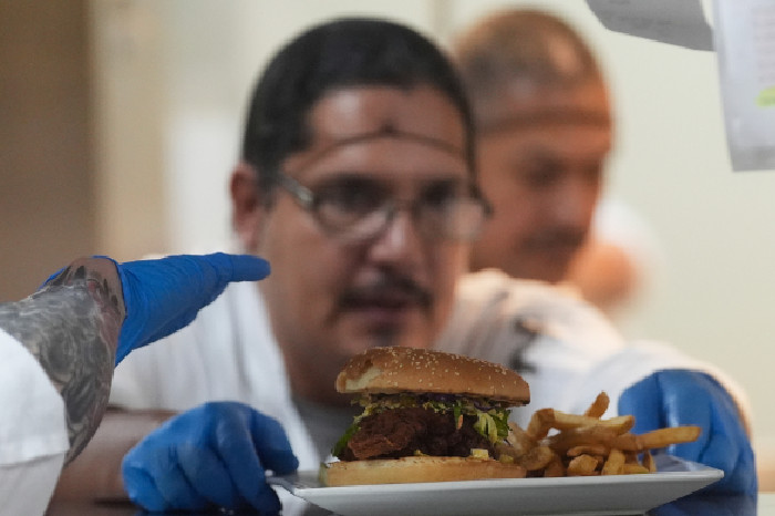 Narapidana Aaron Arroyo menyelesaikan hamburger sebelum mengirimkannya ke meja tamu. Foto: AP